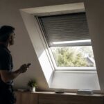 Expert controleert een VELUX rolluik op zonne-energie dat gedeeltelijk vastzit bij een dakraam